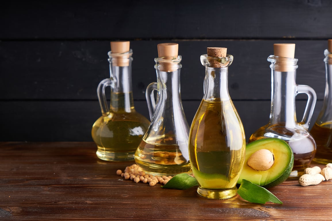 Healthy vegetable oils in glass bottles. Avocado oil, chickpea oil, linseed oil, peanut oil, almond oil. Dark background