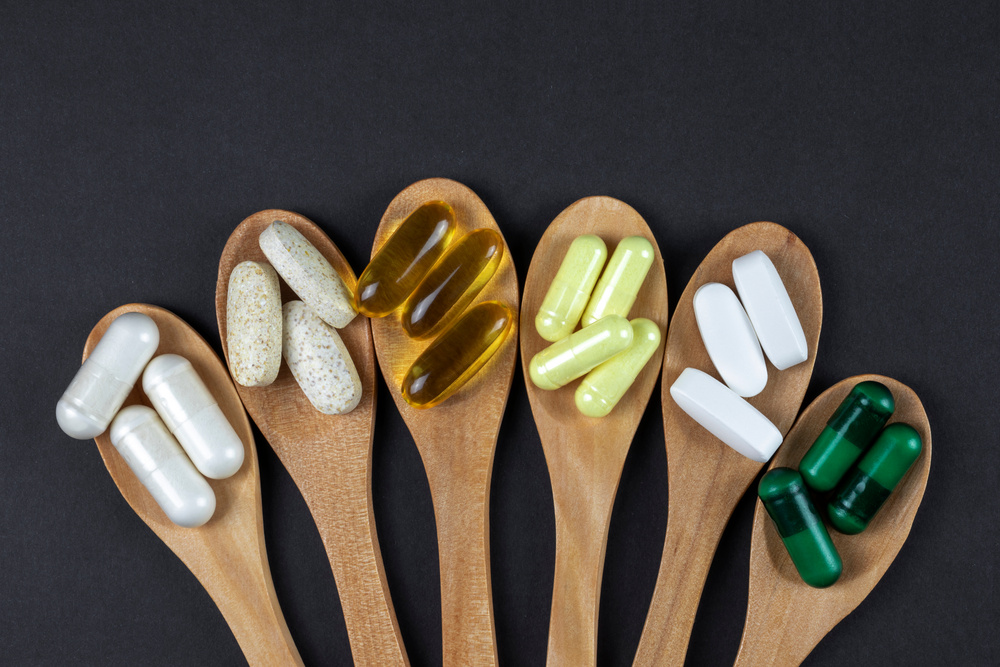 Healthy vitamins and supplements on wooden teaspoons against
